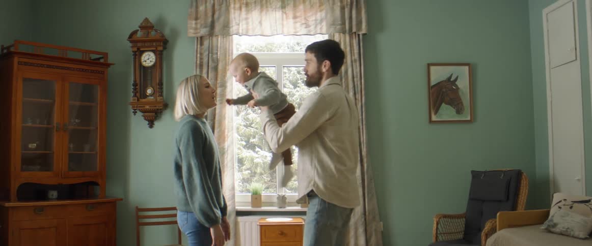 Mom and dad take turns making baby fly around as they play and hug