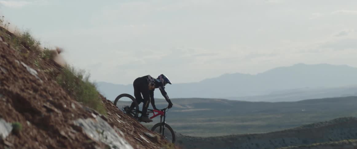 A person carving a mountain bike down the side of a mountain in the desert nature