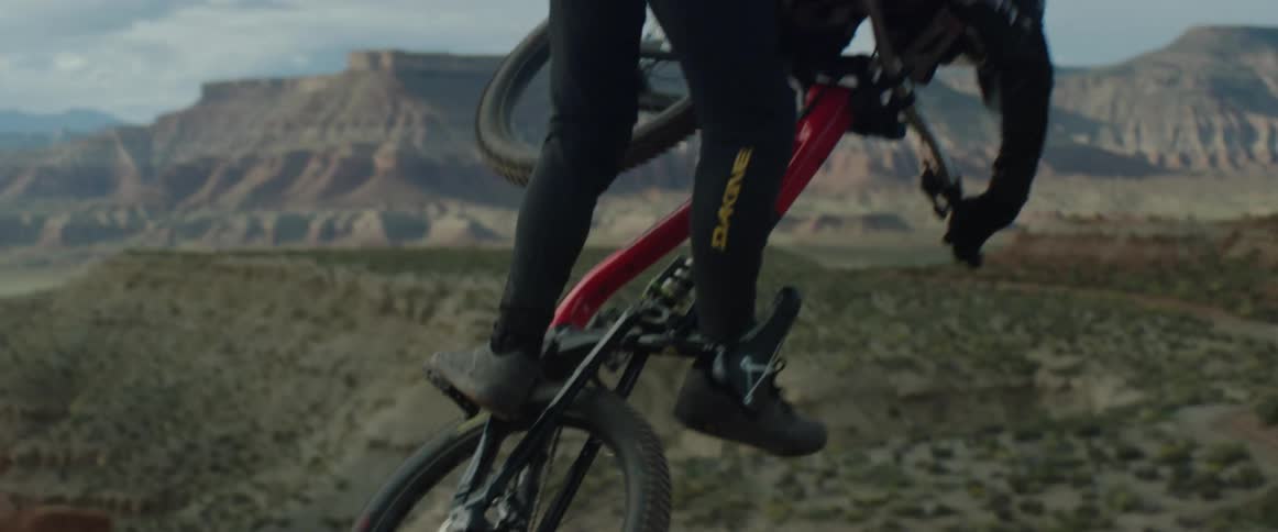 A mountain biker dropping off a desert cliff and pulling a table top trick