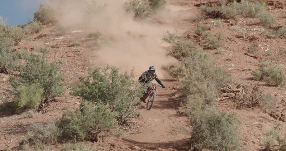 A mountain cyclist kicks up dirt while riding down a steep desert hill