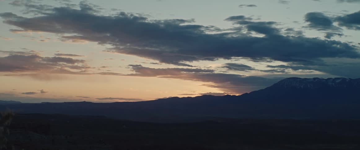 A view of a desert sunset sky across the valley with mountains and clouds