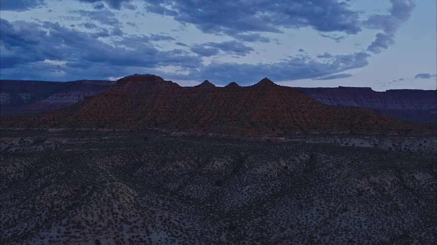Aerial of a red desert landscape with mesas and plateaus and clouds at dusk