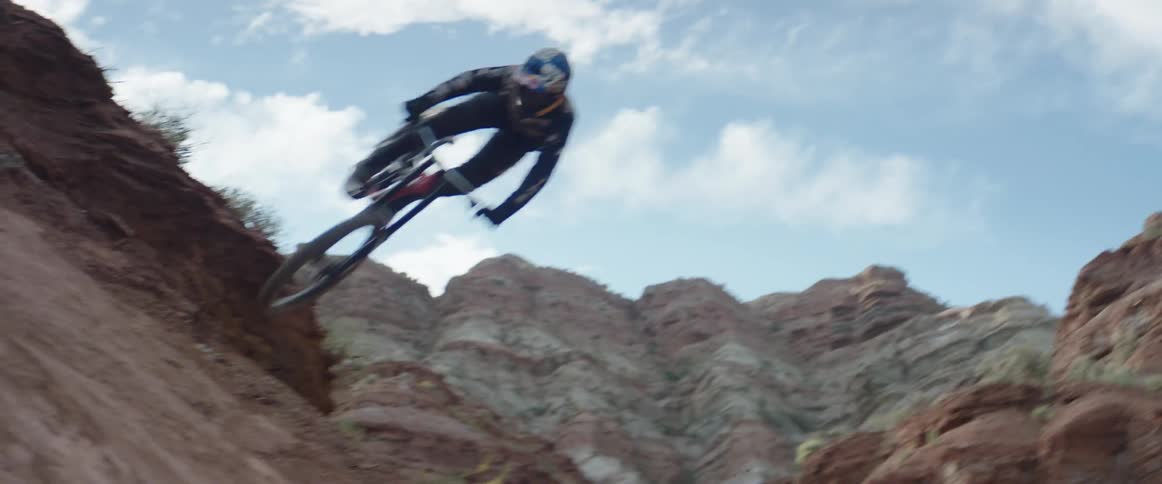 Man riding a mountain bike jumping onto the hip of a mountain slope in the desert