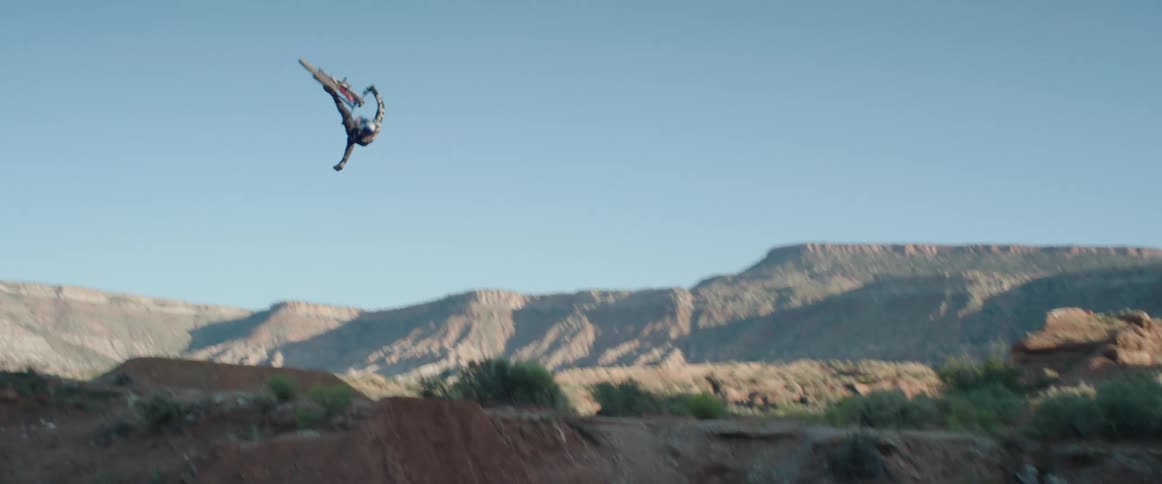 A person doing a flip on a mountain bike while going over a jump in a desert