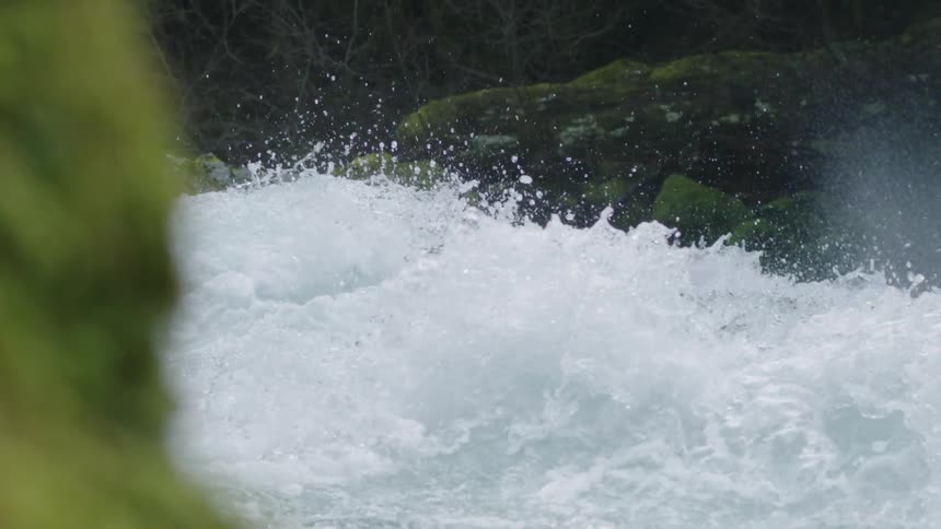 Slow motion shot of whitewater leaping and cascading into the air above the lip of a large waterfall
