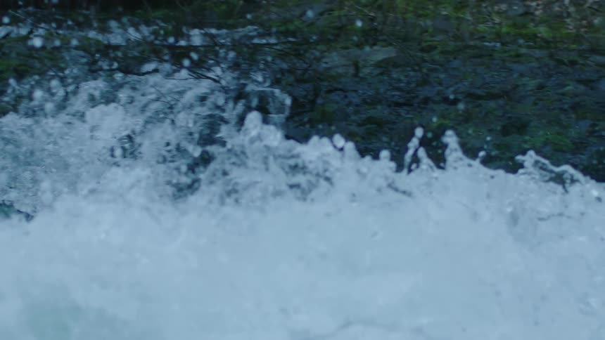 A man in red whitewater kayak rides down a frothing whitewater rapid before paddling downstream