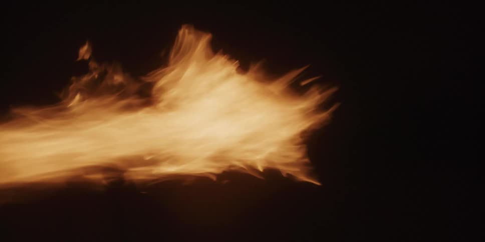 An orange flame burning in front of a black background