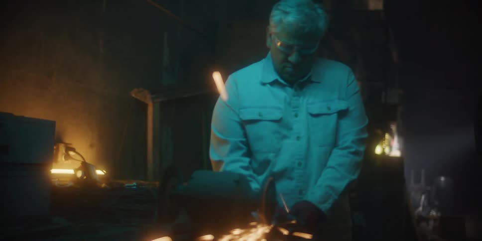 Sparks flying around a man using a power tool in a workshop