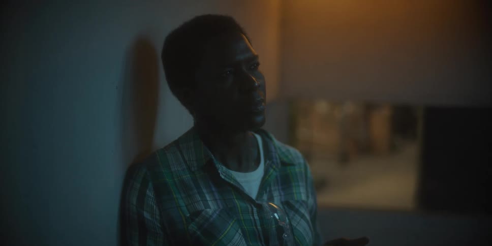 A man standing in a hallway is focused and looking at something in the distance before taking a few steps forward