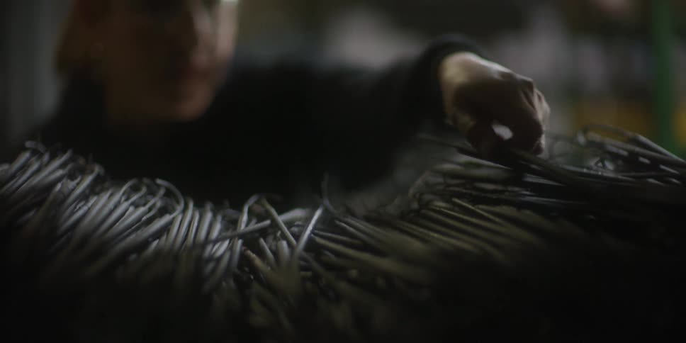 Worker wearing face proctection selects metal rods from a shelf in a warehouse
