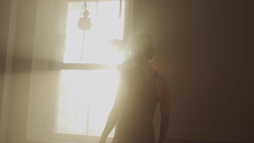 A woman pacing in front of a window