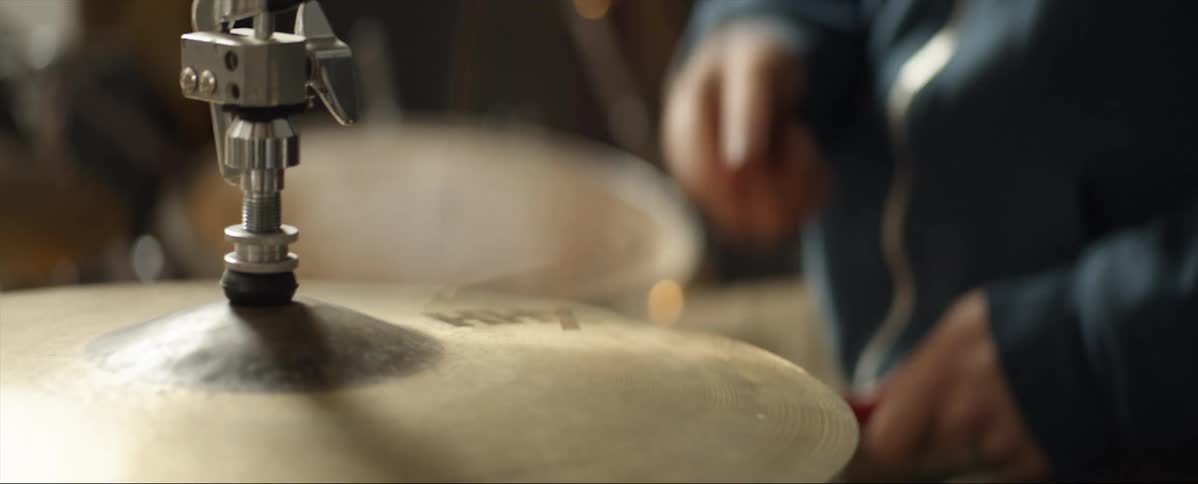 A man is sitting at a drumset hitting a cymbal with a stick