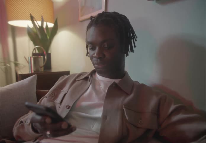 A man scrolling on a smartphone while sitting on a living room sofa