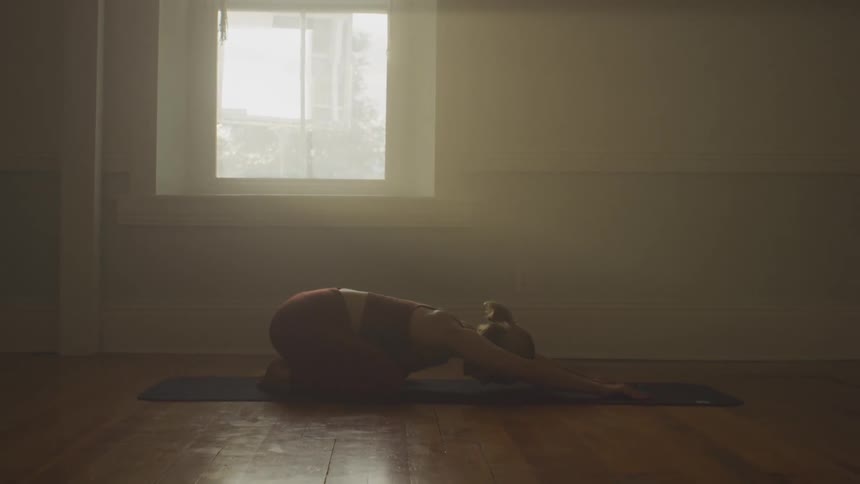 A woman stretches on a mat at home