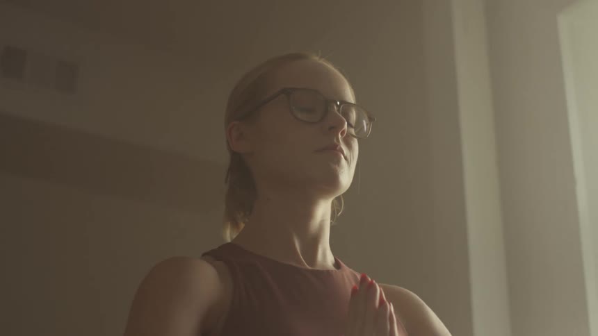 A young woman stands with her eyes closed while performing a yoga pose