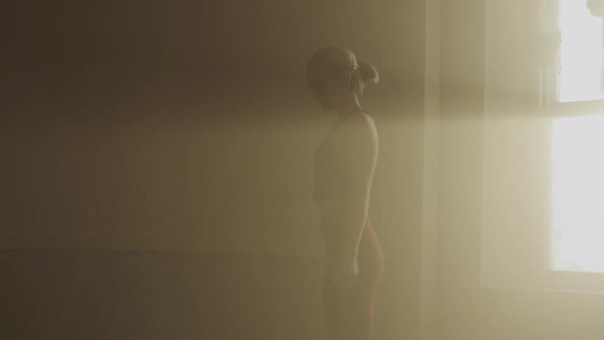 A woman walks as she stretches her arms at home