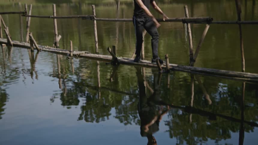 A male dancer practicing outside on a bamboo bridge