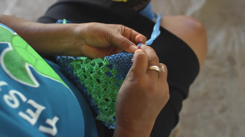 Woman using a crochet needle weaving with colorful threads