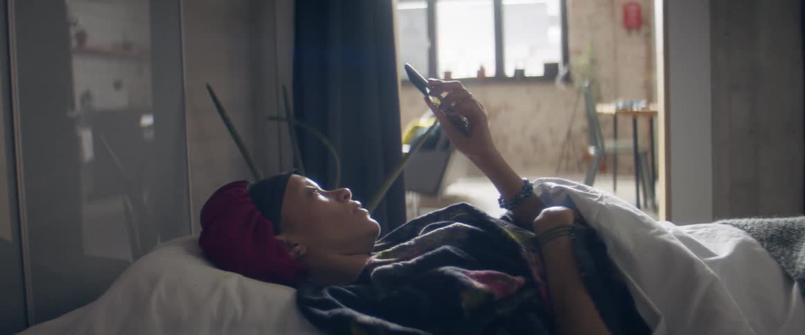 A woman laying in a bed on their phone