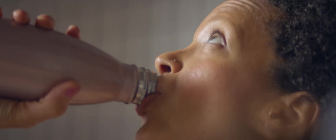Woman drinks water from a thermos bottle at home