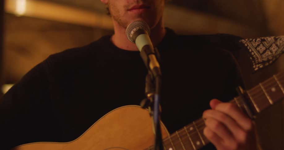 A man sings and plays guitar in a small venue