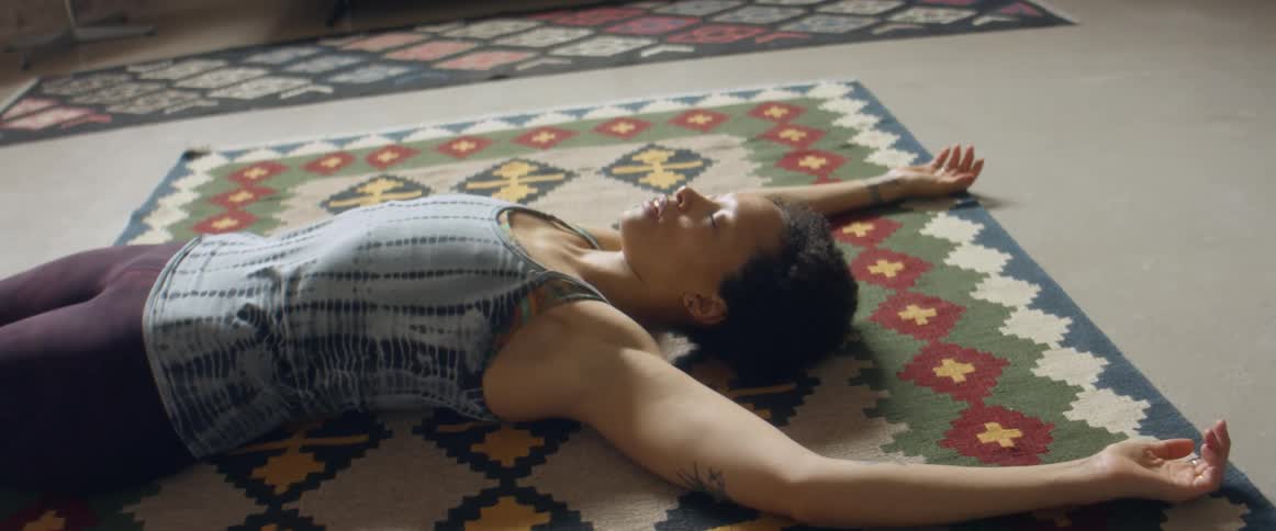 A woman sprawled out and breathing heavily after finishing a home workout