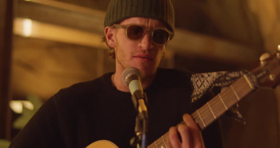 A man is playing a guitar and singing into a microphone