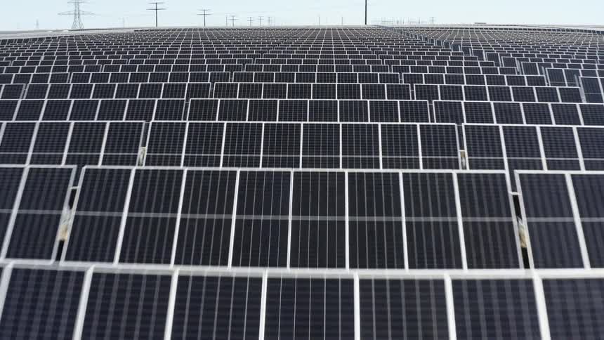 Solar farm with many solar panels and utility towers in the distance