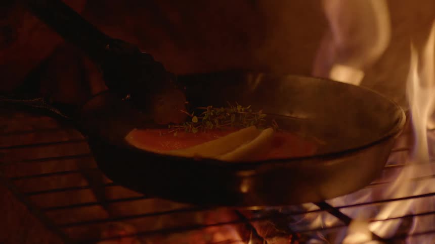 Meat cooking in a pan on an open fire