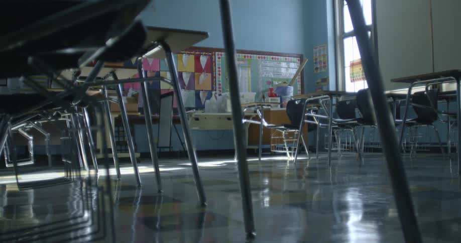 Sunlight reflects off the floor in an empty school classroom with colorful posters on bulletin boards