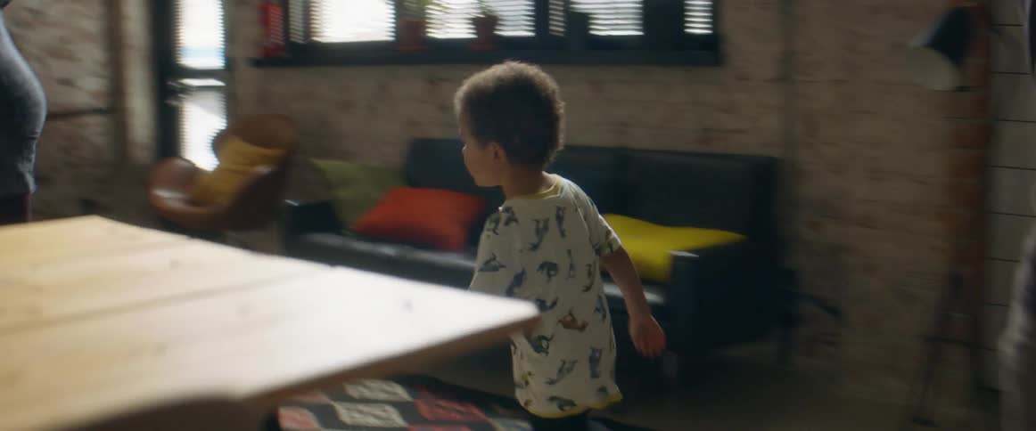 A man a woman a boy and a girl in a room running around a table
