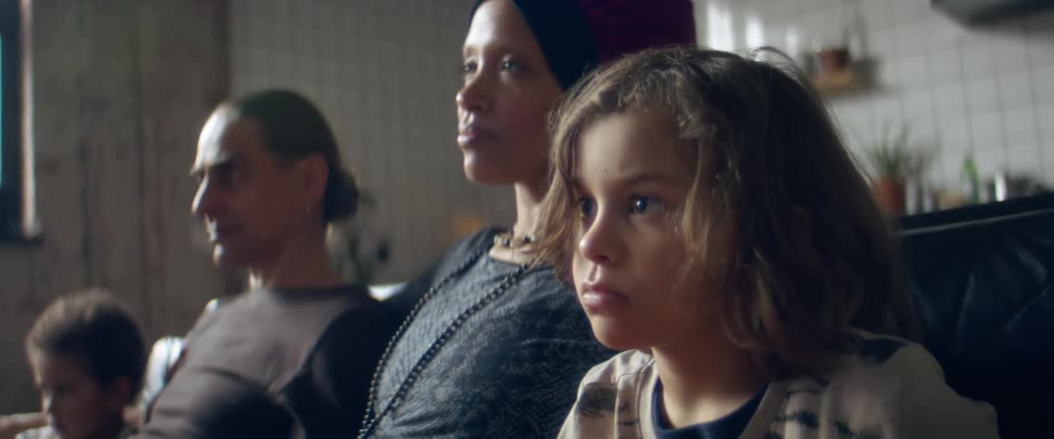 Family of four sitting on a couch at home watching television