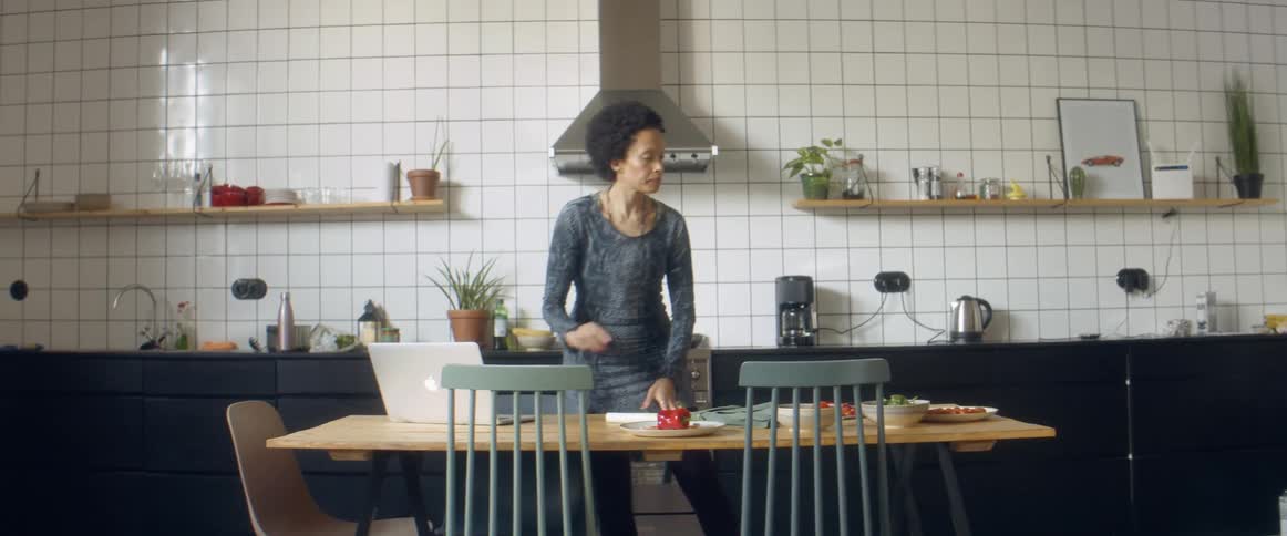 A woman dancing while listening to music and chopping vegetables in a home kitchen