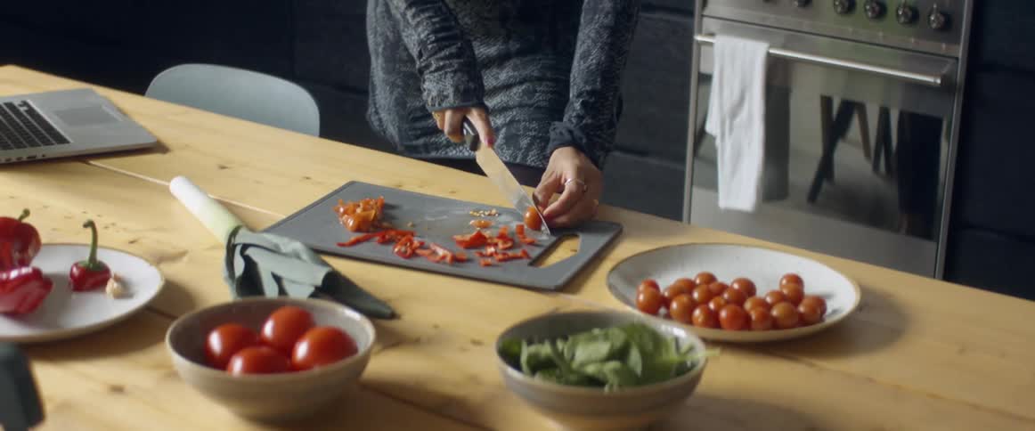 A woman dancing while cutting vegetables in a home kitchen