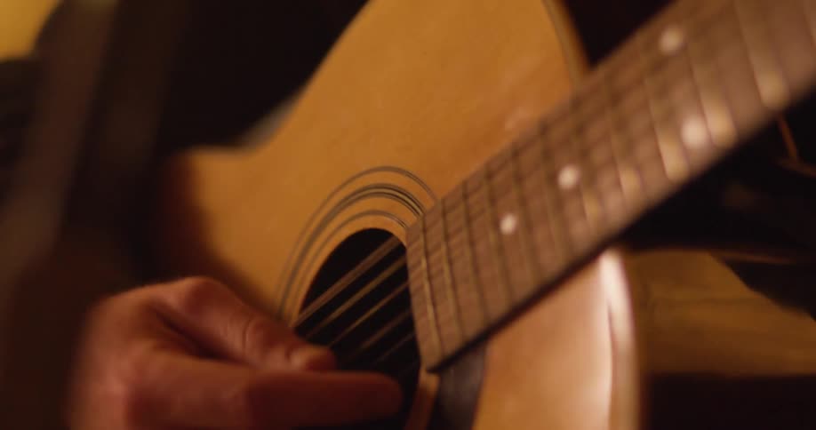 Close up of a persons hands as they play a guitar