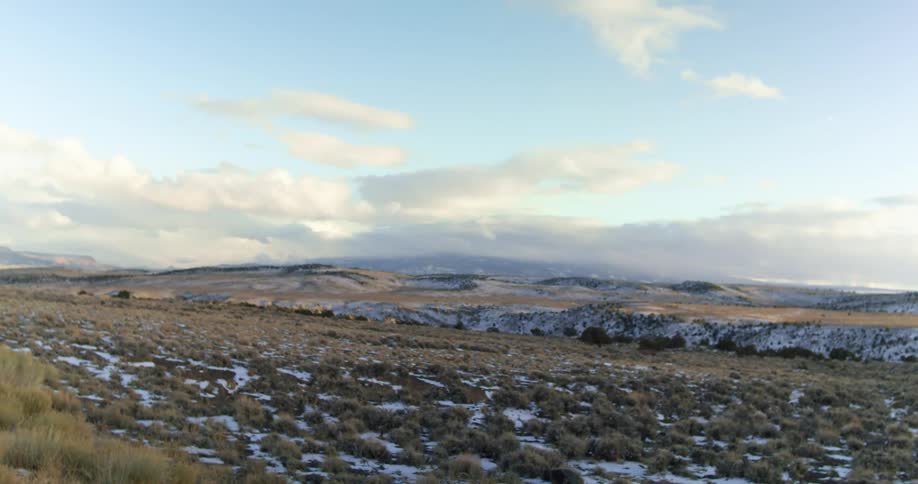 A wide view of a field with hills covered in small bushes with patches of grass