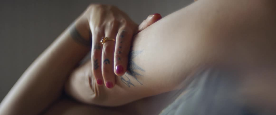 Woman with tattoos and a grey top stretches before exercise