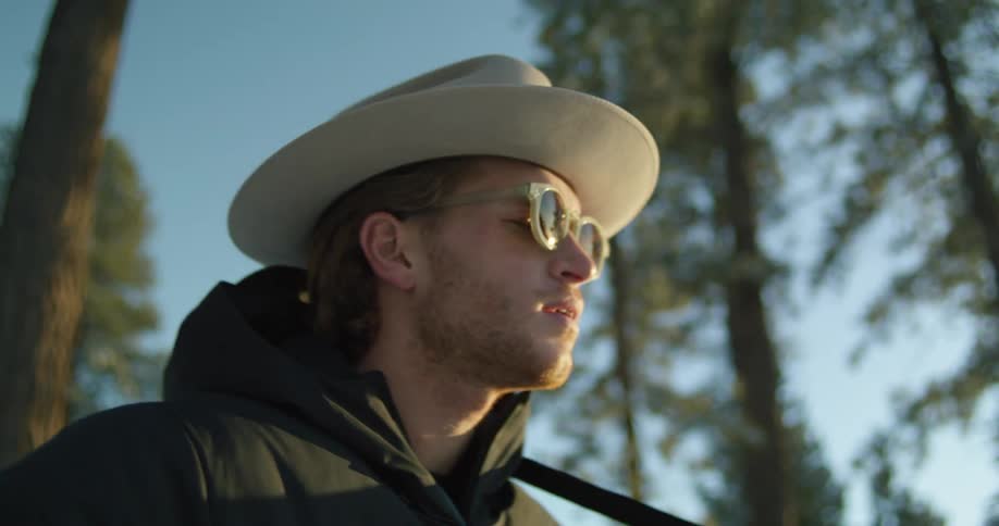A man singing outdoors in a forest while playing a guitar standing up