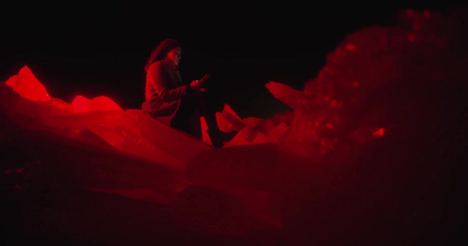 Woman sitting over a pile of ice under red lights at night