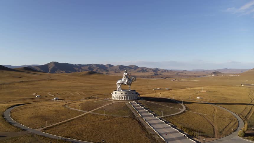 A building with a statue on top with a landscape the sky and clouds in the background