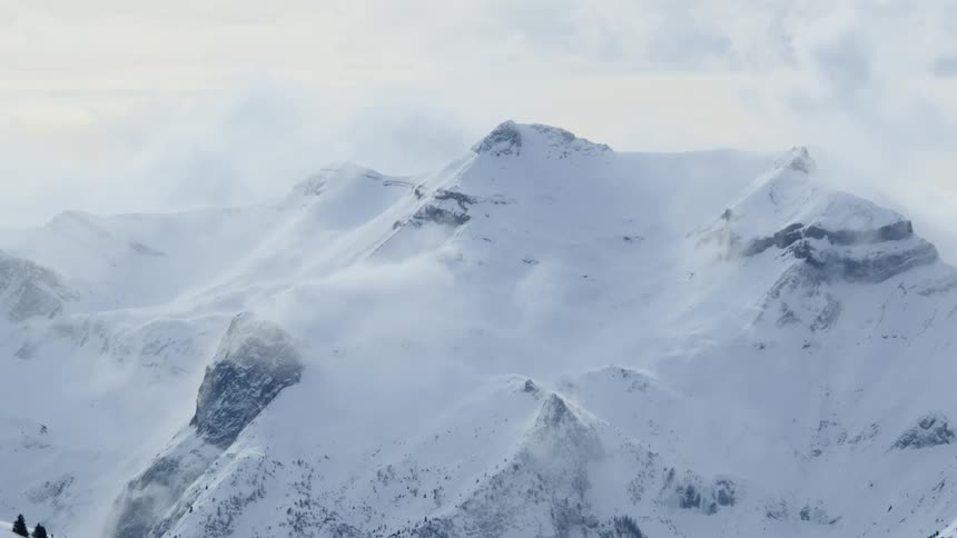 A mountain range covered in snow and ice with the sky and clouds in the background