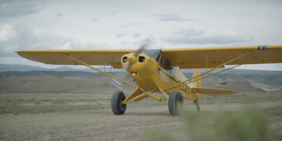 Small yellow plane rolling on a dirt runway