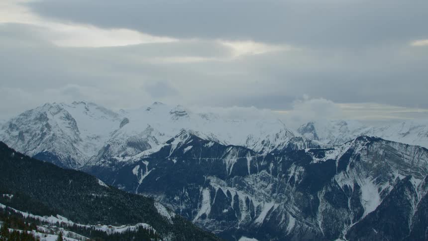 Dense clouds move over a snow covered mountain range