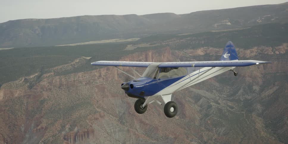 A small airplane flies above a mountain range