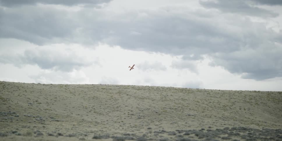 Small plane flying in the distance on a cloudy day