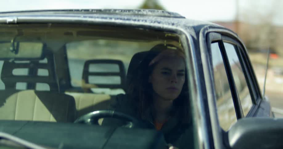 A woman looks around as she drives her car