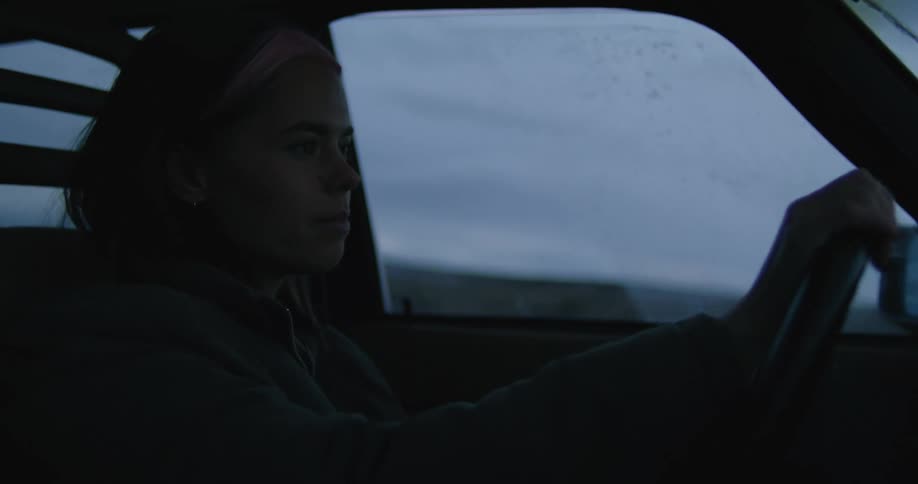 A woman drives with both hands on the steering wheel at night