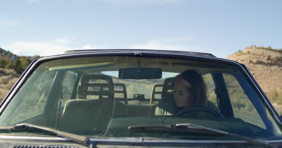 A woman is sitting in a parked car