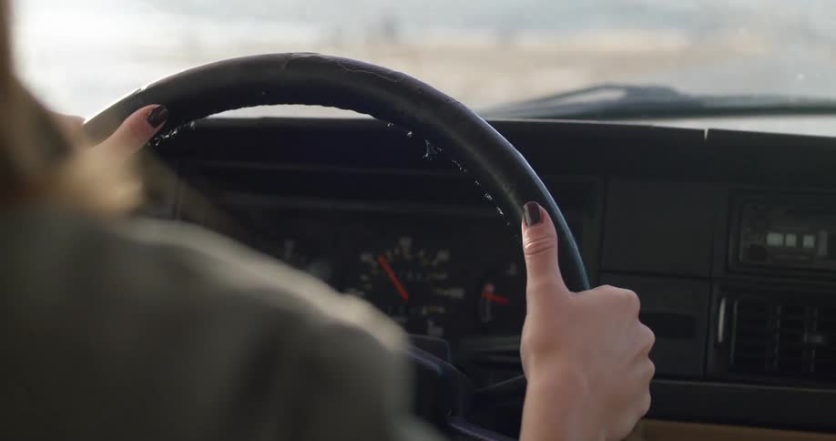 A woman gripping a steering wheel while driving a car