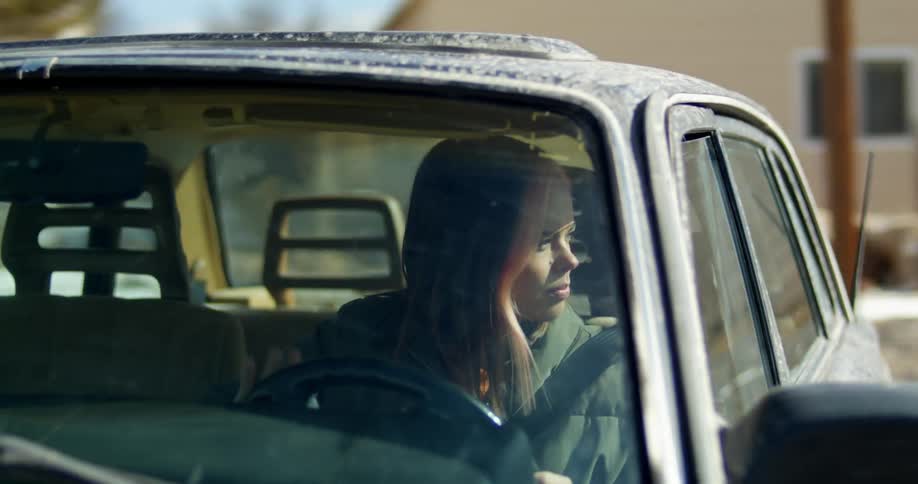 A woman steering a car while driving on a residential street